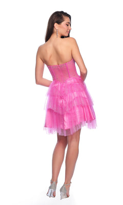 A woman stands in high heels, facing away, wearing the Dave & Johnny Short Glitter Hoco Dress 11878—a strapless pink tulle homecoming dress with sparkles and ruffled layers.