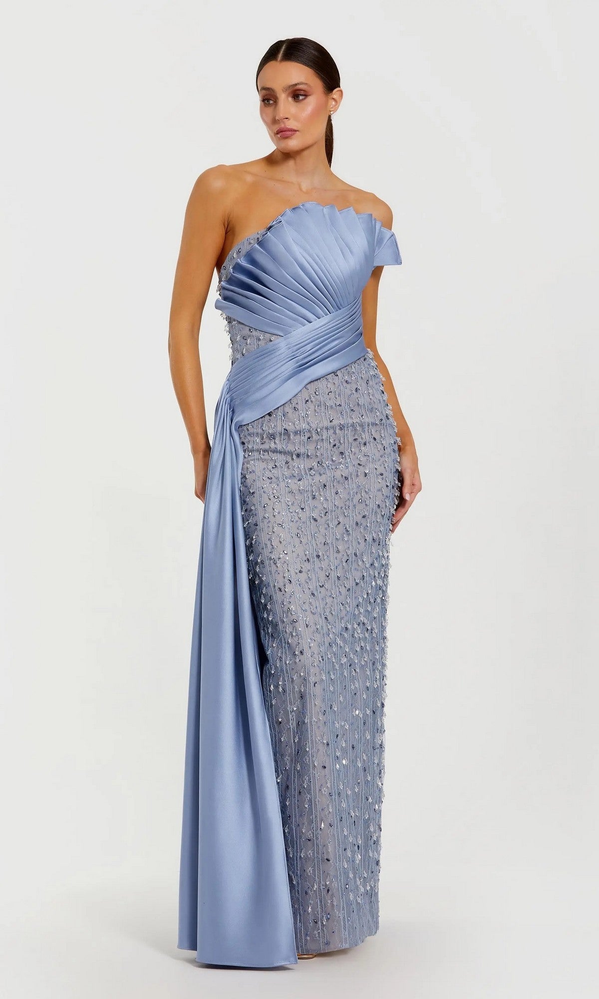 A woman poses against a white background in the Mac Duggal 11909 Long Formal Dress—a one-shoulder, floor-length gown in Fusion Blue, featuring pleated satin details and beaded embellishments.