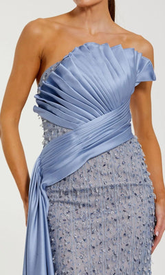 A woman wearing the Mac Duggal 11909 long formal dress, a blue beaded strapless gown featuring pleated satin details and elegant embellishments.