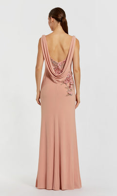 A woman stands facing away against a plain background, wearing the Mac Duggal 11910 Cowl-Neck Long Formal Dress in blush pink with a low cowl back and floral embroidery.