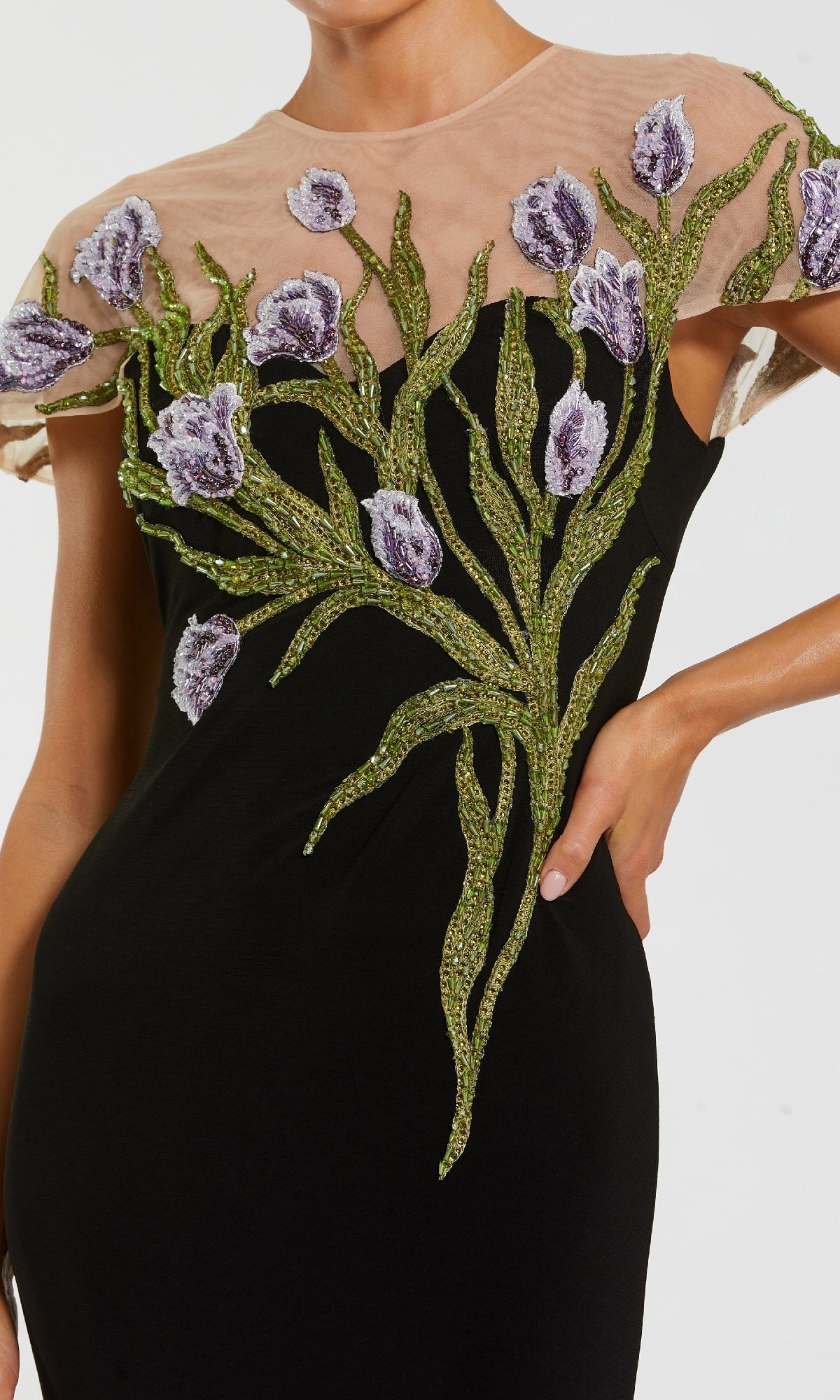 A close-up of the Mac Duggal 11912 Long Beaded-Tulip Formal Dress—a black gown with sheer neckline and intricate purple-green floral embroidery on the chest and shoulders.