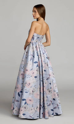 A woman poses in the Mac Duggal 11921 long formal dress—a strapless blue floral ballgown with a light pink and blue pattern—standing slightly to the side against a plain background.