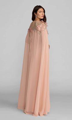 A woman wearing the Long Formal Dress: Mac Duggal 11942 in light pink, featuring a flowing silhouette with sheer detailing and intricate 3D floral appliques on the shoulders, stands against a plain gray background.