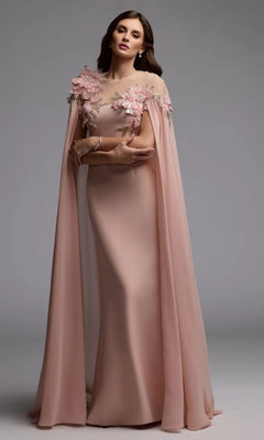 A woman stands against a plain gray background wearing the Mac Duggal 11942 long formal dress—a floor-length, pale pink gown featuring sheer cape sleeves and intricate 3D floral appliqué details on the shoulders.
