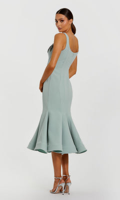 Woman wearing the Midi Wedding Guest Dress: Mac Duggal 11948, a fitted light blue sleeveless midi dress with flared hem, paired with silver high-heeled sandals, standing against a plain white background.
