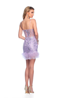 A woman faces away, wearing the Lilac Purple Homecoming Dress 11958 with sequin details, sheer back panels, and tulle trim, paired with high-heeled sandals, against a white background.