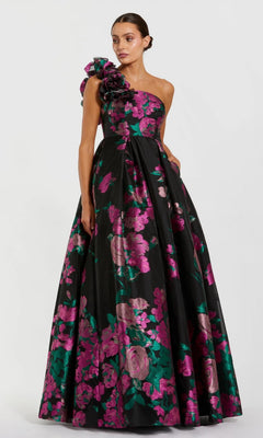A woman wears the Mac Duggal 11967 long formal dress in Black Multi—a floor-length, one-shoulder ballgown featuring pink and green floral prints and a dramatic shoulder ruffle.