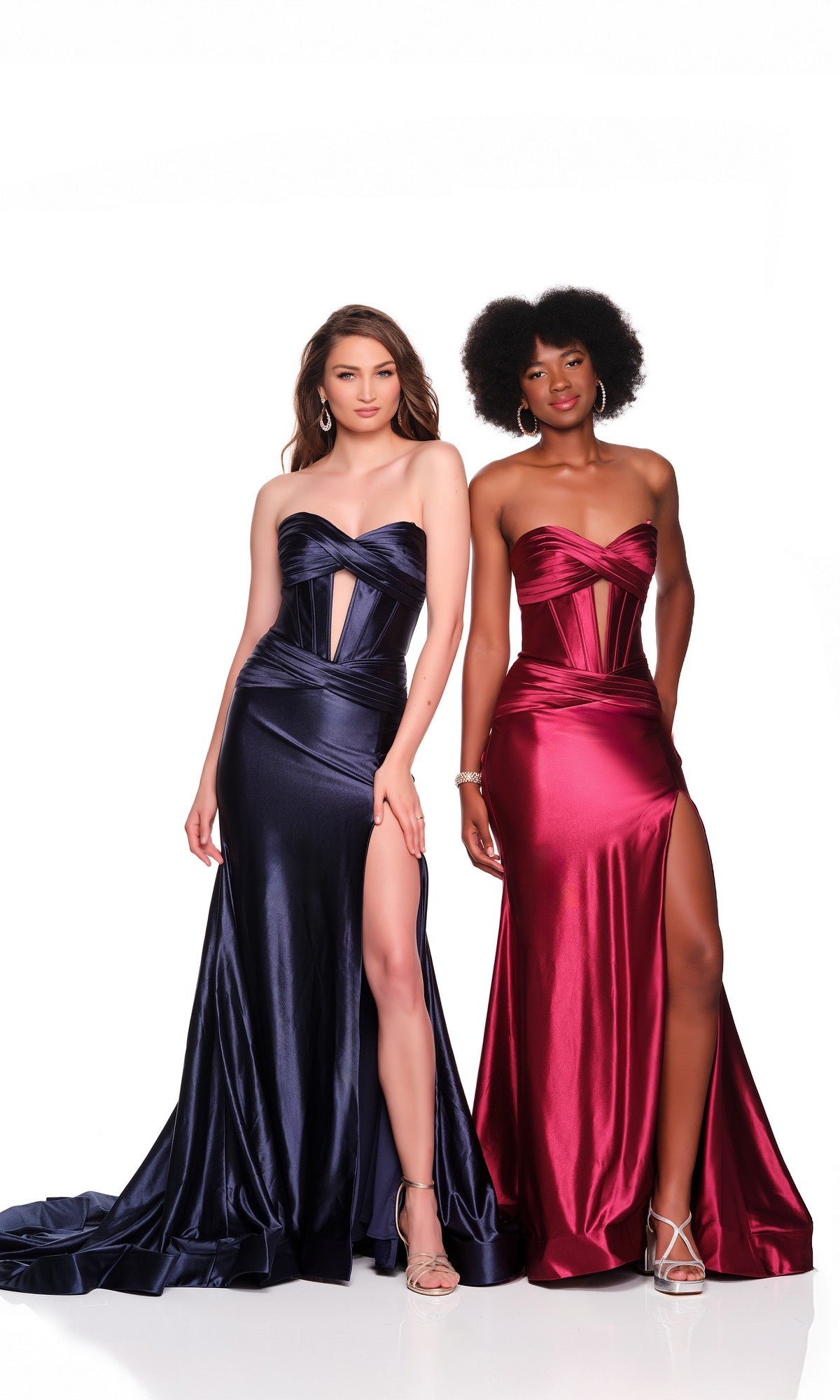 Two women stand side by side against a white background, each wearing the Dave and Johnny 11975 Strapless Corset Prom Dress—one in navy blue, the other in deep red—with floor-length skirts and high slits.
