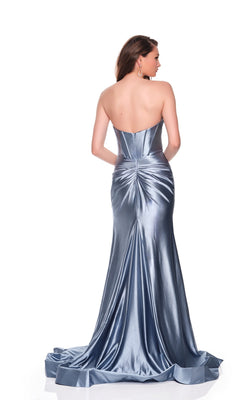 A woman stands facing away in the Strapless Corset Prom Dress: Dave and Johnny 11975, a floor-length metallic silver gown that highlights its smooth, shiny fabric and gathered back detailing.