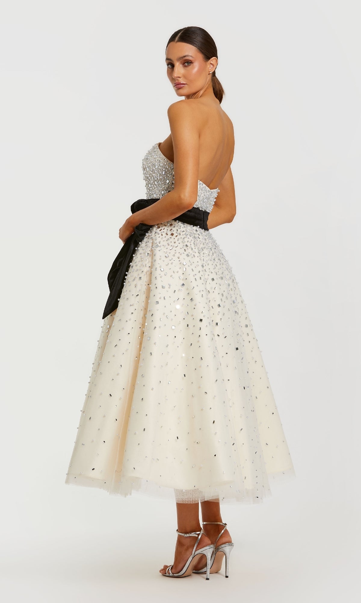 Woman wearing a white evening gown with black embellishments on a white background