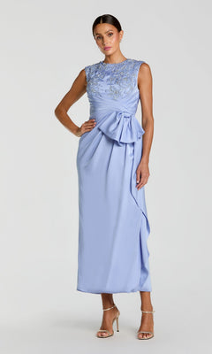 Woman in the Mac Duggal 11989 satin wedding guest dress in powder blue with a sleeveless floral and beaded embroidered bodice, draped waist bow, column skirt, and strappy heels.
