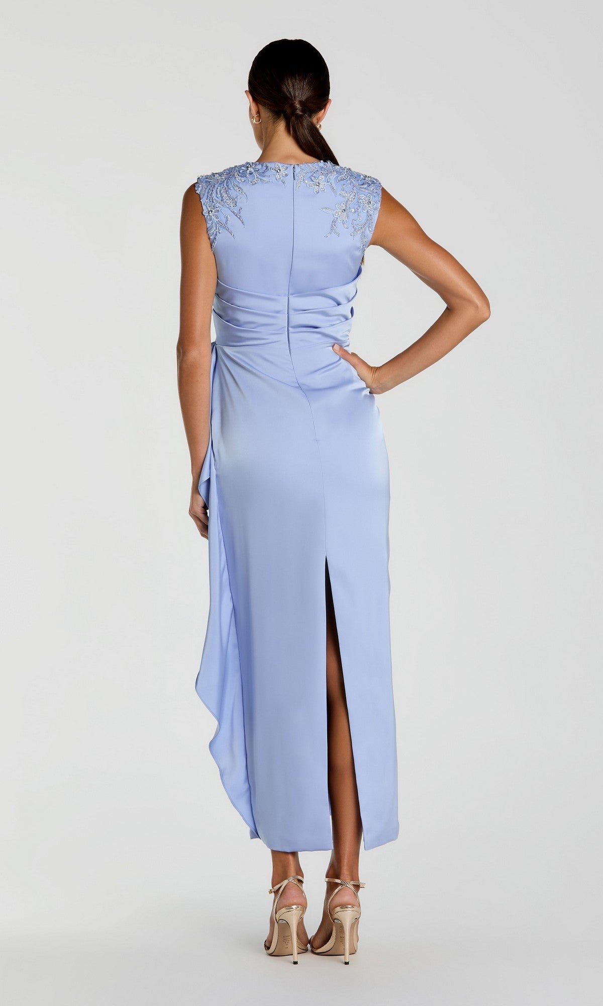 A woman wearing the Mac Duggal 11989 Satin Wedding Guest Dress in light blue, featuring beaded embroidered shoulders and a column skirt, stands with her back to the camera and beige heels.