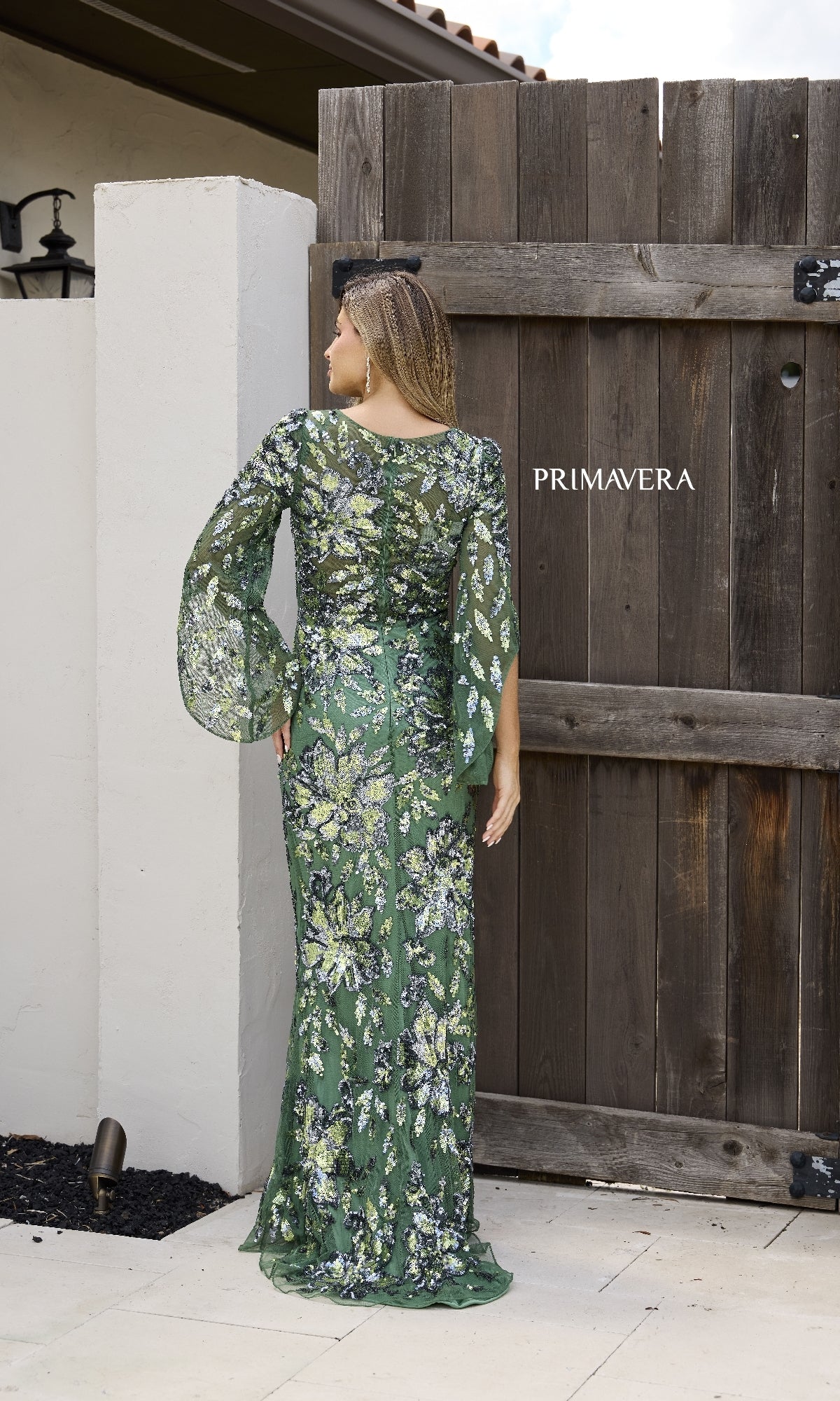 A woman wearing the Primavera 12171 long formal dress in green, featuring sheer long sleeves.
