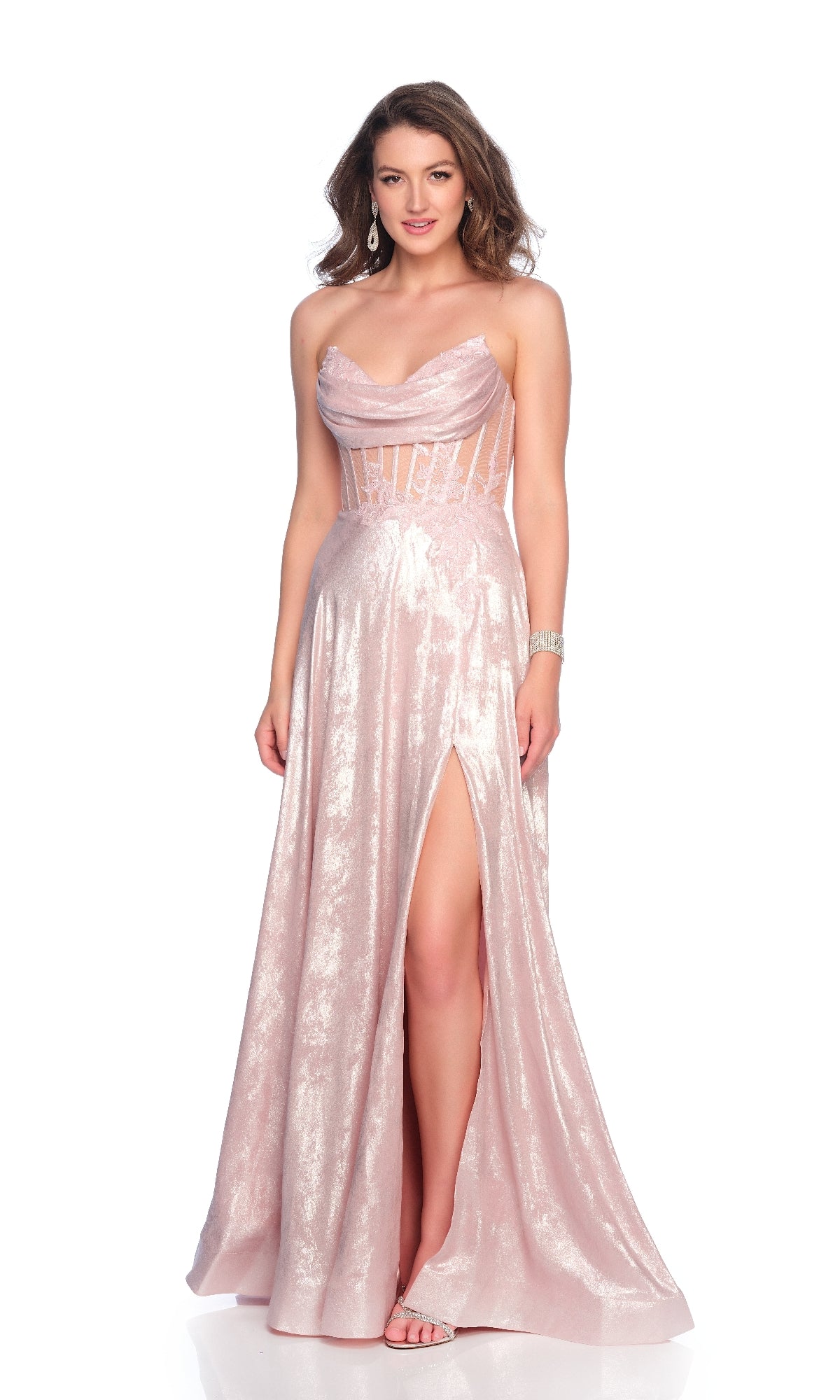 A woman stands against a white background in the Dave & Johnny 12182 light pink prom dress featuring a strapless design, shimmery sheer corset bodice, and high slit.