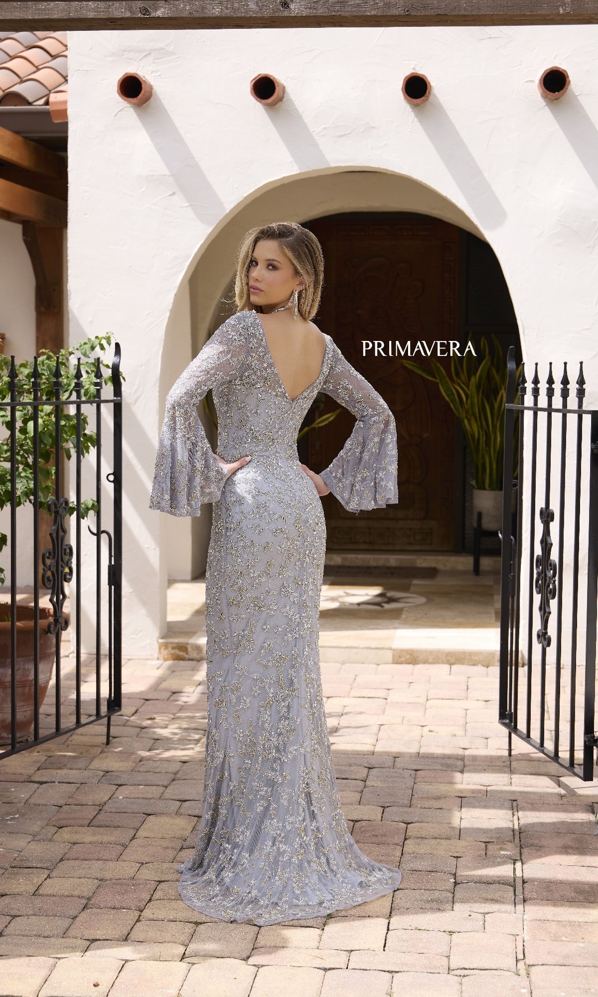 A woman wearing the Primavera 12185 long formal dress, featuring intricate beading and a v-neckline.
