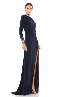 A woman stands elegantly in a studio, wearing the Mac Duggal 12231 one-shoulder long formal dress—an evening gown with silver-embellished cuffs, navy blue fabric, and a high slit.