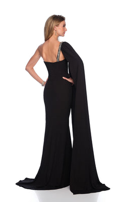 A woman stands facing away against a white background, wearing the Long Black Prom Dress: Dave & Johnny 12232, featuring a one-shoulder design, draped cape detail, and elegant corset bodice.