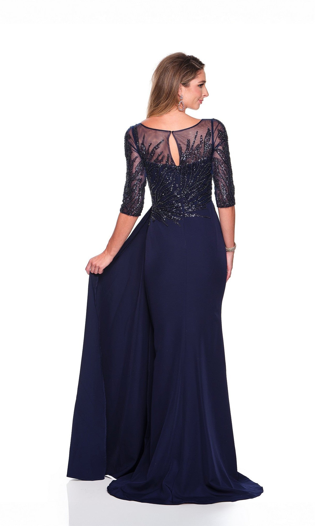A woman poses against a white background, wearing the Dave and Johnny 12363 long formal dress featuring a navy blue chiffon embellished bodice, sheer beaded sleeves, and a floor-length sheath skirt.