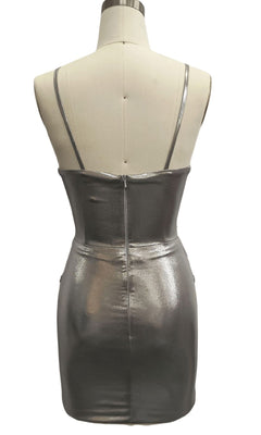 The Short Silver Hoco Dress: 12394 is a metallic silver mini dress with thin straps and a back zipper, shown on a mannequin facing backward—an ideal choice for parties.