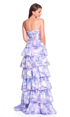A woman wears the Dave and Johnny 12400 long prom dress, a tiered, purple and white floral A-line gown with thin straps, standing with her back visible and the flowing floor-length skirt displayed.