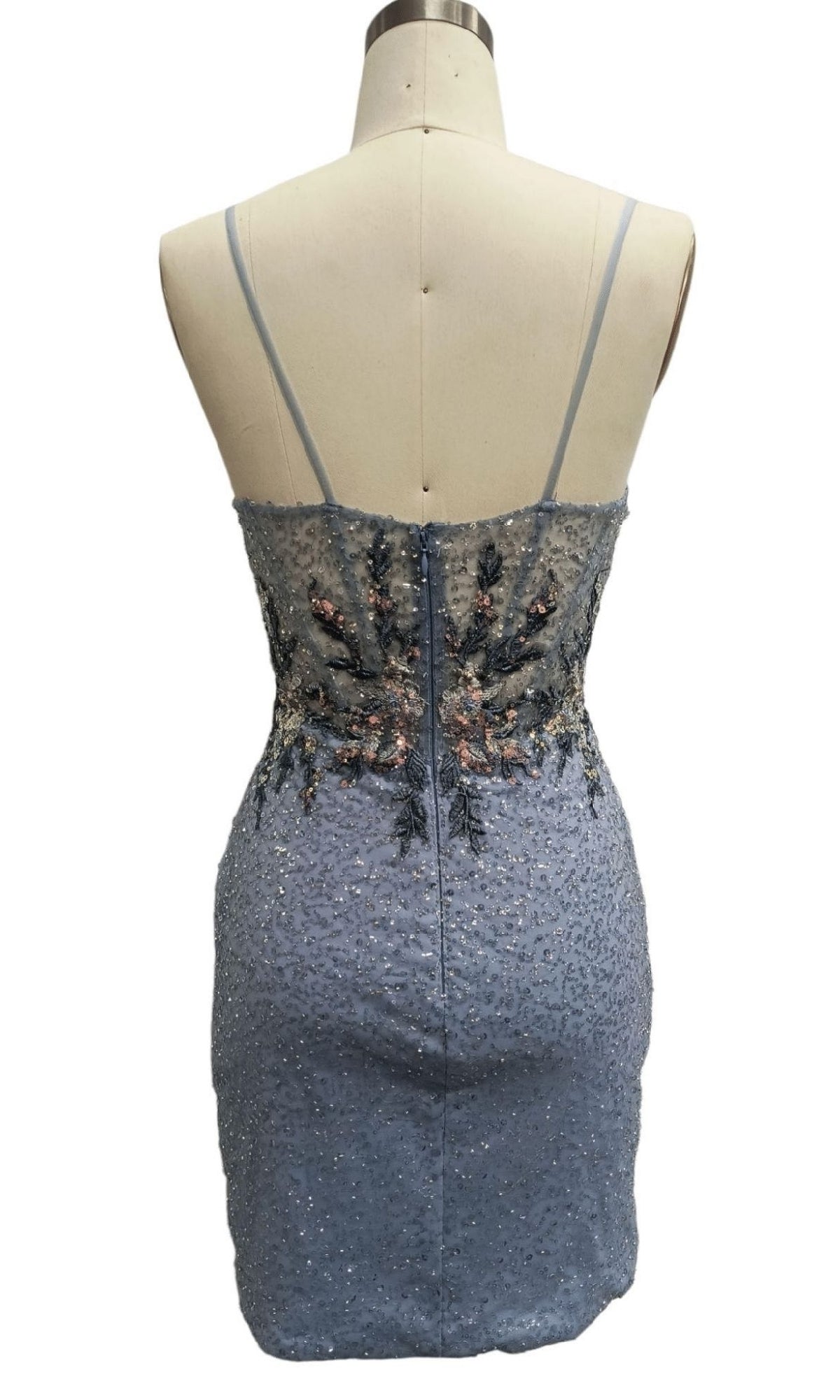 A mannequin displays the Short Blue Homecoming Dress: 12442, featuring a sequin-embellished back view with thin straps and floral embroidery on the bodice.