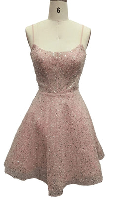 The Short Pink Sequin Hoco Dress: 12461 is a sleeveless, knee-length designer party dress in light pink with thin straps and sparkling sequin embellishments, displayed on a dress form.