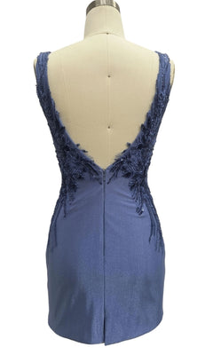 The V-Back Short Blue Hoco Dress: 12462 is a sleeveless, short blue dress with a deep V-back, adorned with floral lace and beaded appliqué on the upper back, shown on a dress form.