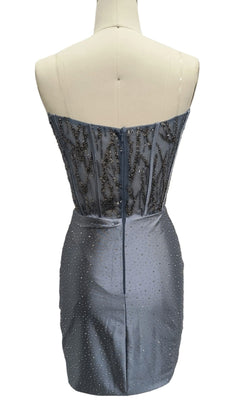 Back view of Strapless Blue Hoco Dress: 12482, featuring a beaded bodice and scattered rhinestones on the short blue skirt; displayed on a dress form for a sparkly designer look.