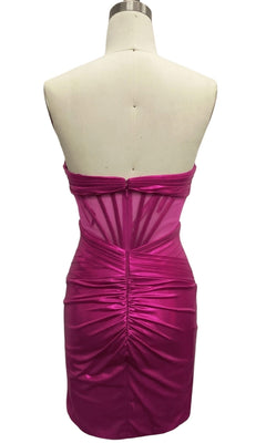 A mannequin showcases the back of the Strapless Fuchsia Pink Hoco Dress: 12565—a fitted, shiny short dress with ruched details, sheer panel accents, and a stylish party-ready look.