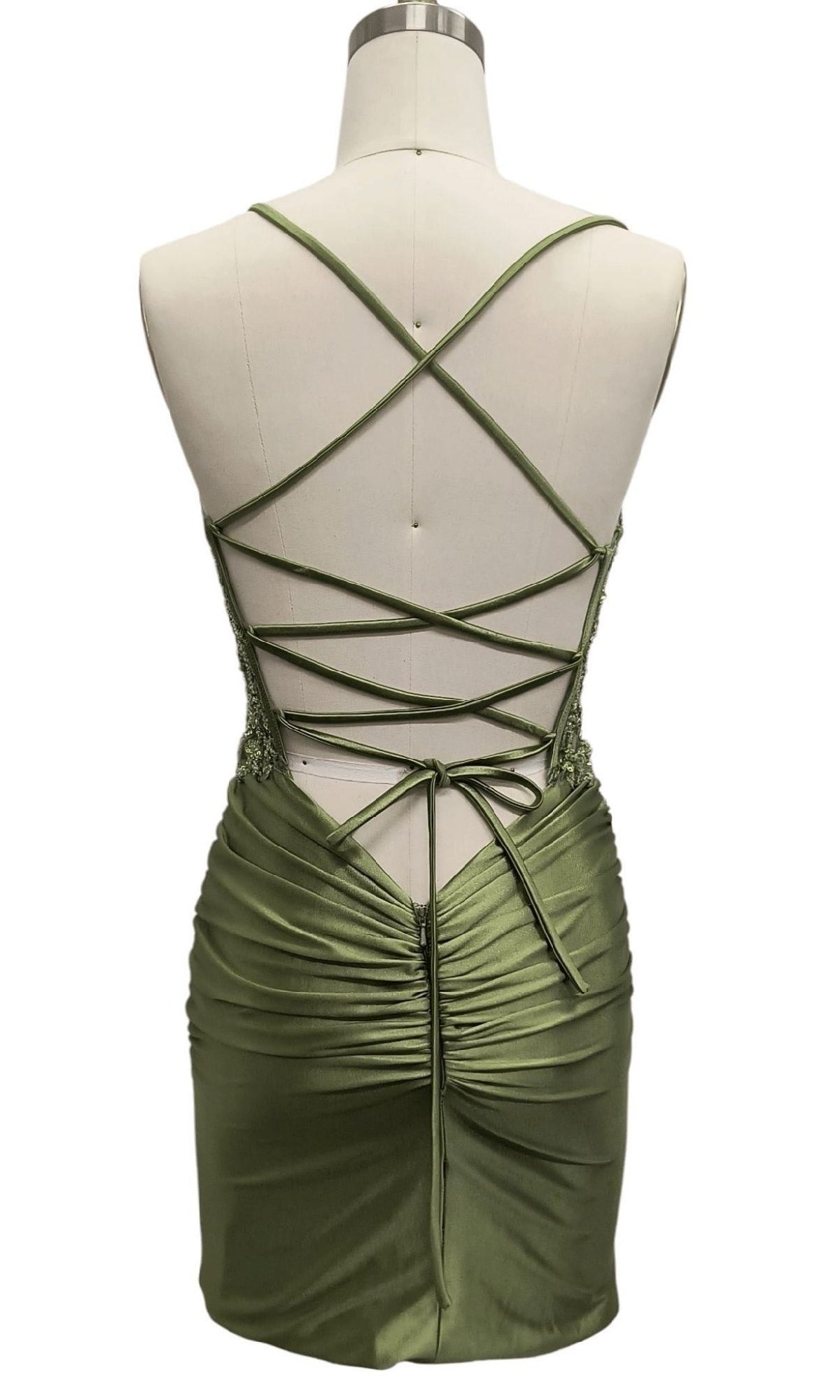Back view of the Sage Green Short Hoco Dress: 12584, featuring crisscross spaghetti straps, lace-up back, ruched lower half, and a stylish sleeveless design.