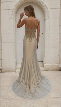 Woman in a elegant dress with intricate back design standing in front of a stone archway.