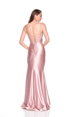 A woman is shown from the back in the Long Prom Dress: Dave and Johnny 12899, a pink fitted gown with spaghetti straps, a lace-up hot-stone embellished corset, and a floor-length satin skirt.