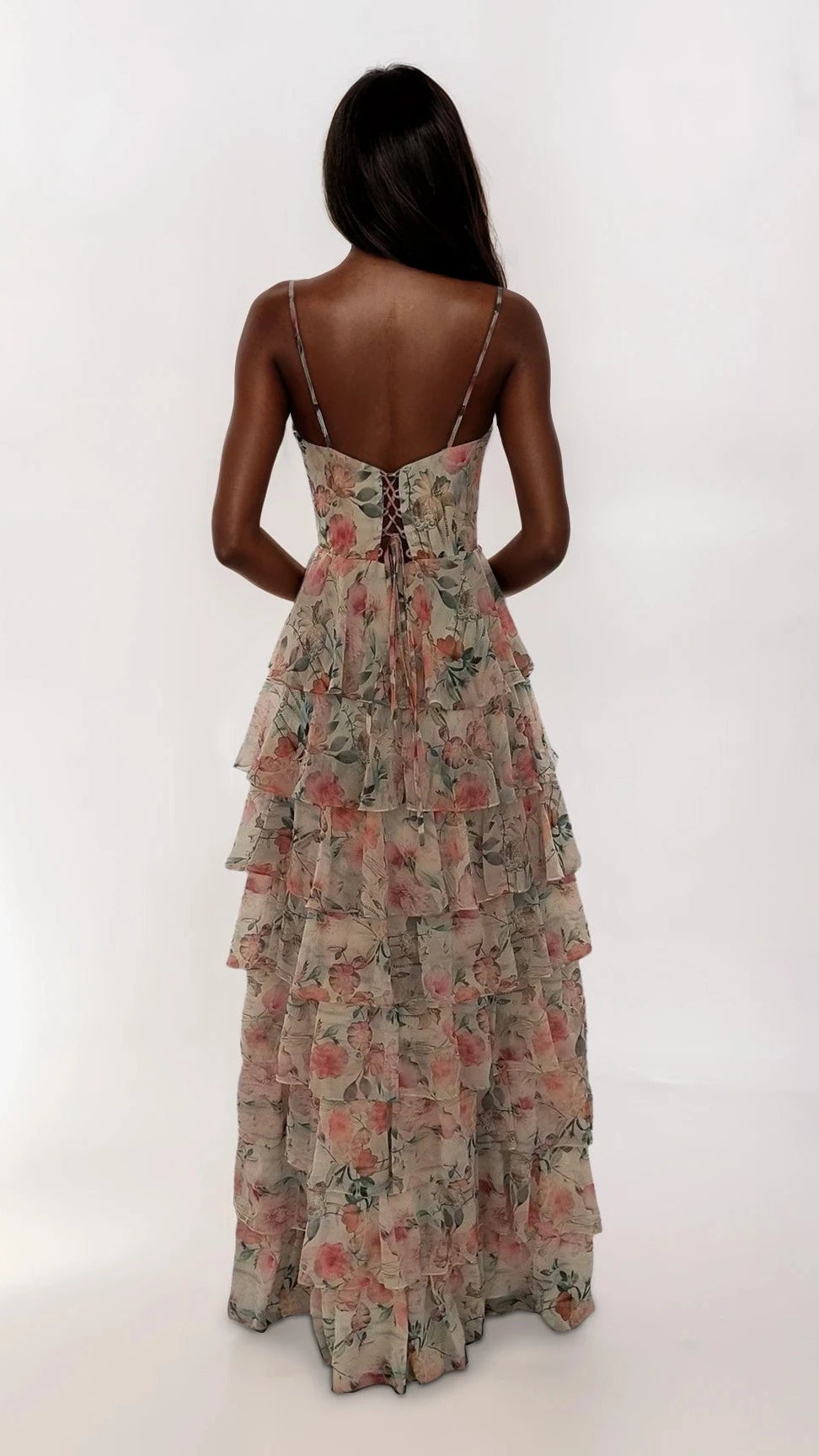 A woman with long dark hair models the Dave and Johnny 12948 long prom dress—a sleeveless white floral gown with a corset bodice, tiered ruffle skirt, and lace-up back—standing against a plain white background.
