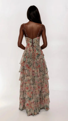 A woman with long dark hair models the Dave and Johnny 12948 long prom dress—a sleeveless white floral gown with a corset bodice, tiered ruffle skirt, and lace-up back—standing against a plain white background.