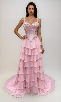Woman in a pink Dave & Johnny 12966 long tiered A-line prom dress with a fitted, bead-trimmed corset bodice and spaghetti straps, standing against a plain light background.