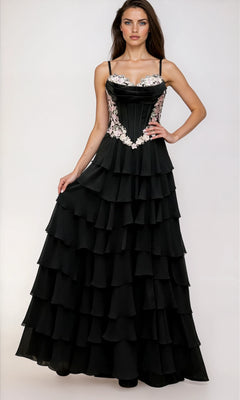 A woman stands against a plain light background, wearing the Dave & Johnny 12966 Long Tiered A-Line Prom Dress—a black gown with thin straps and floral embroidery on the bodice.