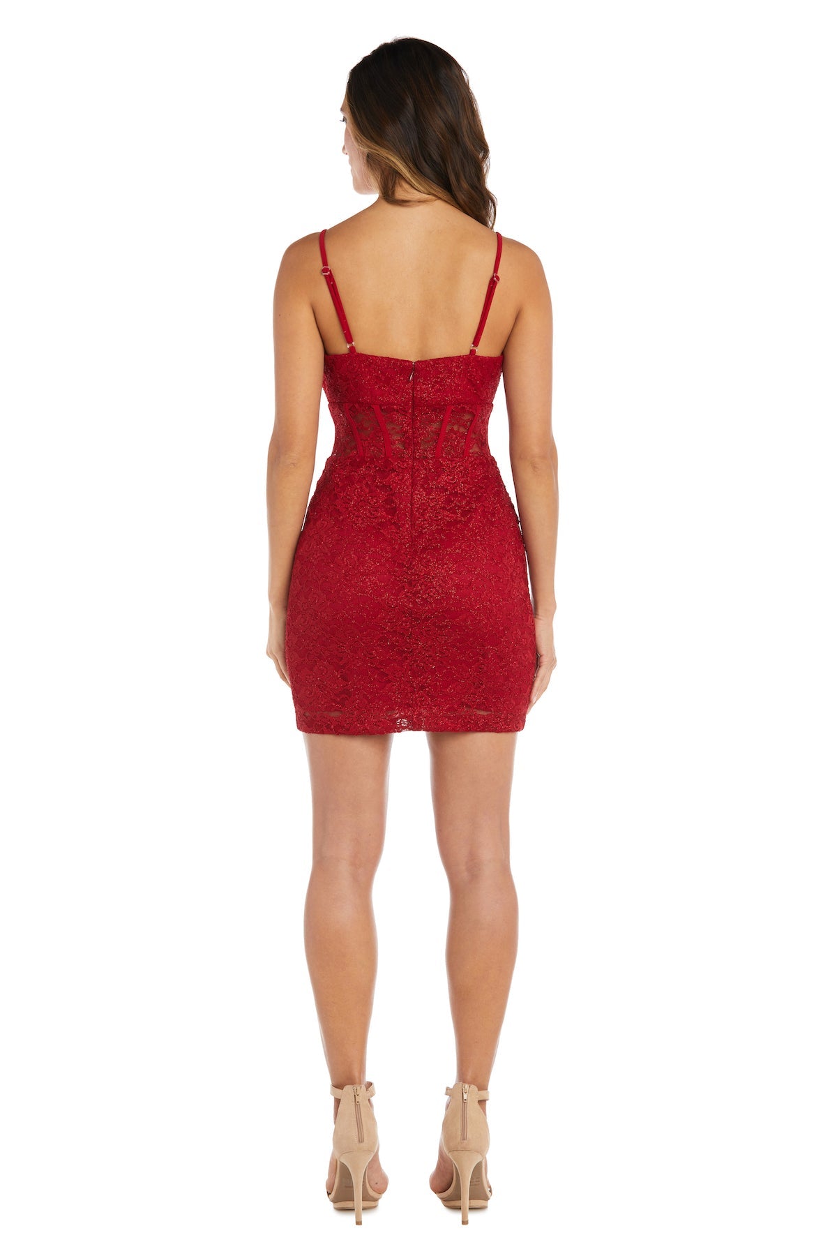 A woman faces away wearing the Morgan 12976 short lace party dress, featuring a fitted red design with a delicate corset bodice and thin straps, paired with nude high-heeled shoes.