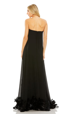 A woman with long blonde hair stands facing away, showcasing the back of a strapless black Strapless Trapeze Formal Gown: Mac Duggal 13001 with a feathered hem.