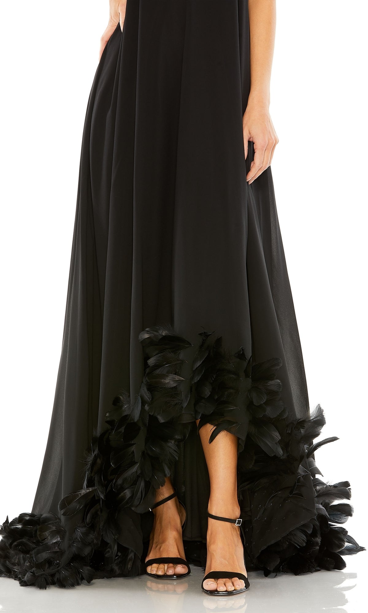 A woman wearing the Mac Duggal 13001 Strapless Trapeze Formal Gown with feather-trimmed hem and black strappy high-heeled sandals.