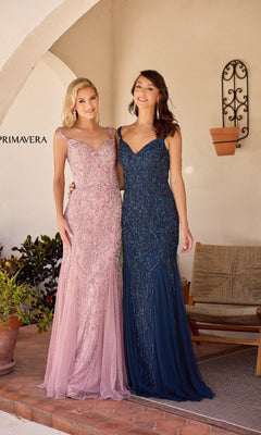 Two women pose side by side on a simply decorated patio, each wearing the Primavera 13143 long formal dress—one in pale pink, the other in dark blue—both featuring sparkly embellishments.