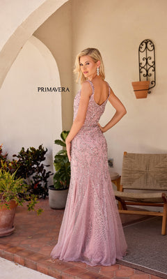 A woman in the Primavera 13143 long formal dress—a sleeveless, floor-length pink sequin gown with a sweetheart neckline—stands on a patio, posing near plants and outdoor furniture as she looks over her shoulder.