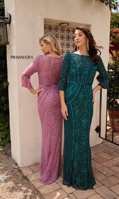 Two women stand outdoors in Primavera 13151 long formal dresses—one pink lace, the other green—both with delicate bell sleeves, facing away from the camera.