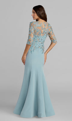 A woman stands with her back to the camera, wearing the Mac Duggal 13204 long formal dress in light blue, featuring lace and floral embroidery on the upper half and a floor-length silhouette.