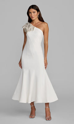Woman wearing the Mac Duggal 13221 Tea-Length Party Dress in ivory, featuring a crepe one-shoulder design and embellished floral shoulder applique, poses against a plain gray background.