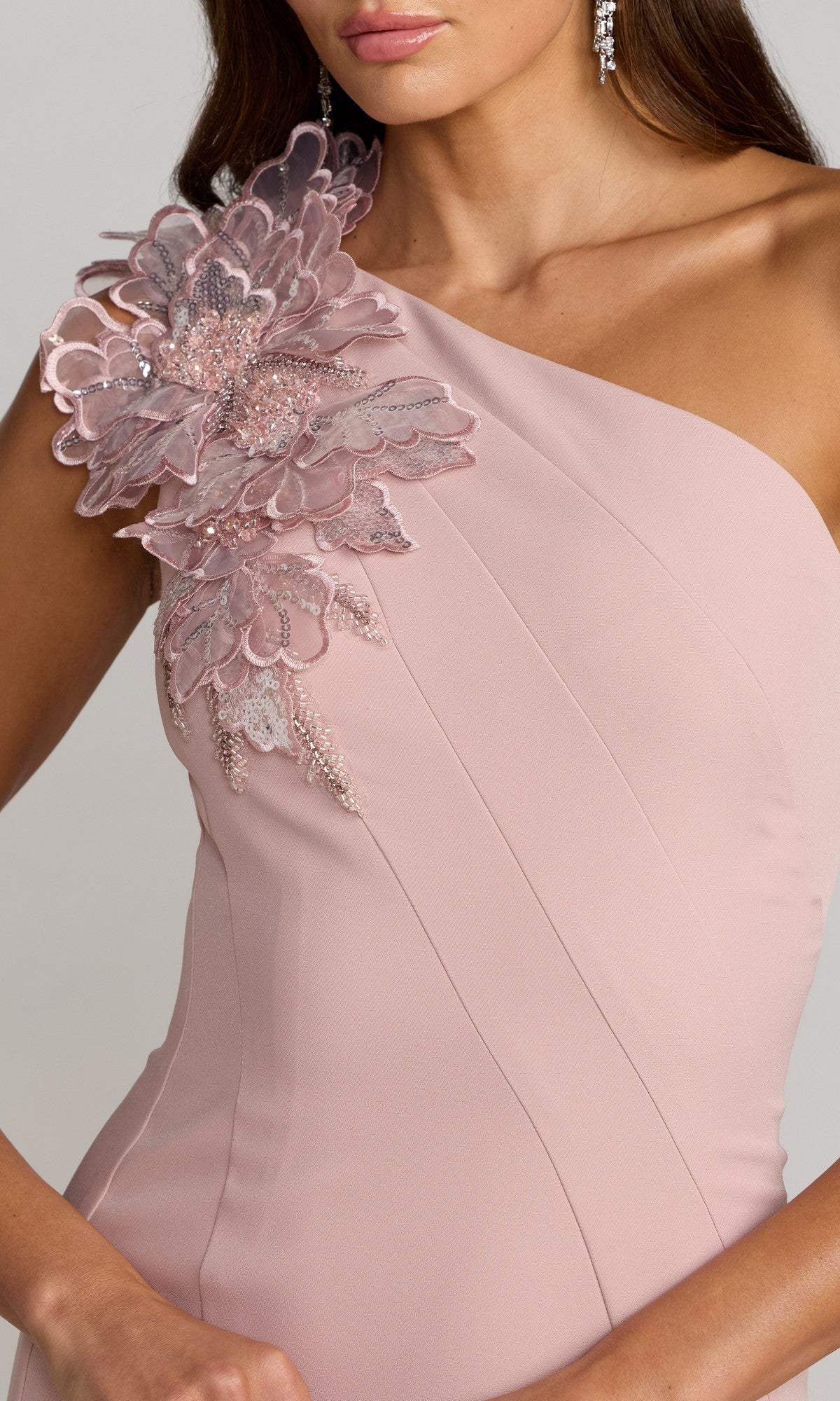 A woman in the Tea-Length Party Dress: Mac Duggal 13222, a light pink one-shoulder crepe midi dress adorned with a large 3D floral embellishment on the shoulder.