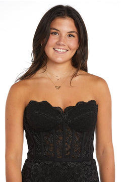 A young woman with long dark hair smiles at the camera, wearing the Strapless Long Lace Prom Dress: Morgan 13269 and a gold necklace, against a plain white background.