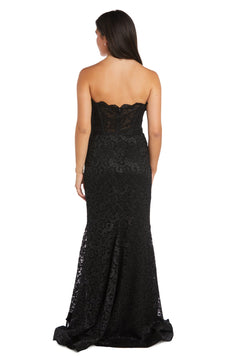 A woman stands with her back to the camera, wearing the Strapless Long Lace Prom Dress: Morgan 13269—a floor-length black lace mermaid gown with a slight train.