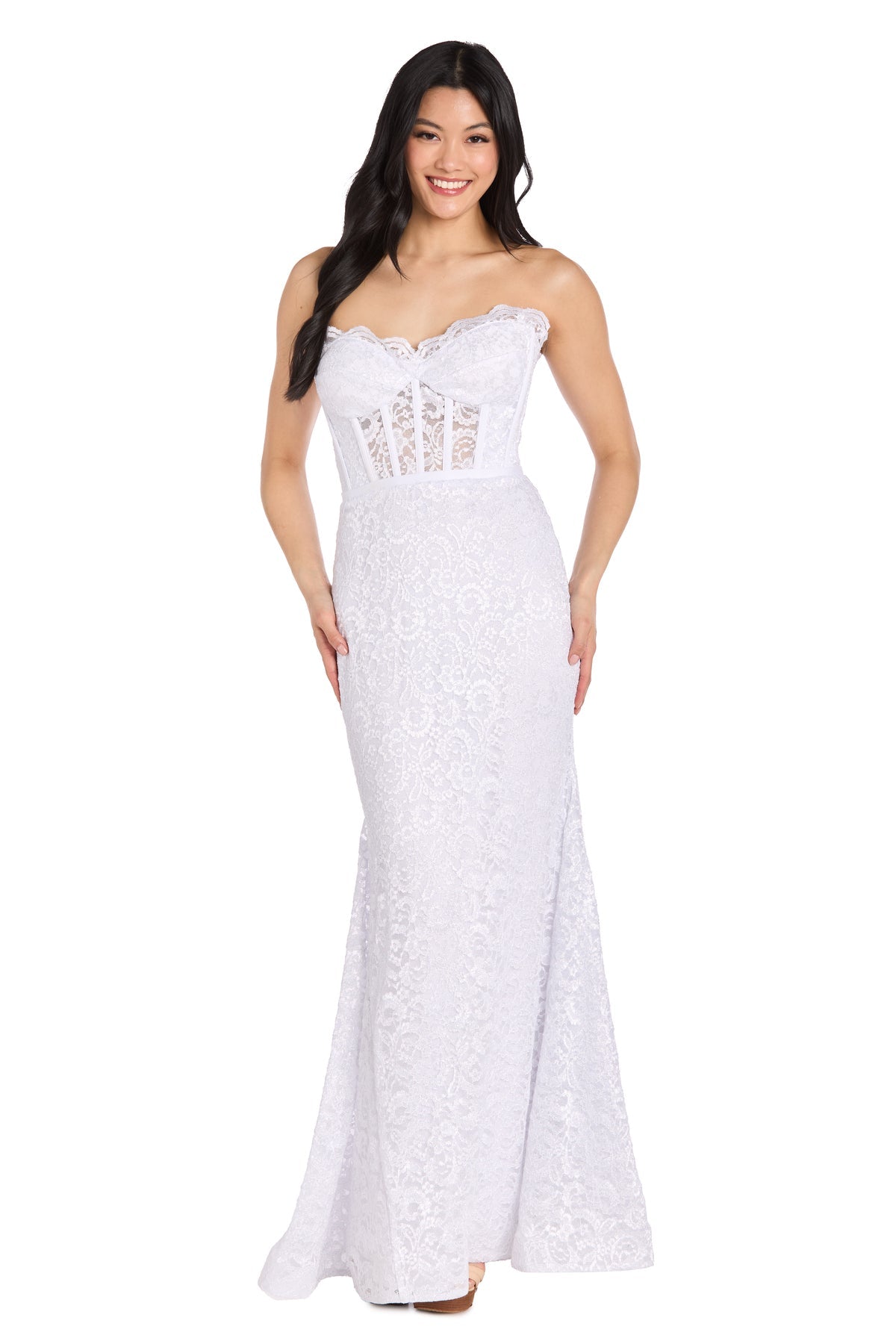A woman wearing the Strapless Long Lace Prom Dress: Morgan 13269 stands and smiles at the camera; the dress features a fitted bodice, flared mermaid skirt, and elegant white lace design.