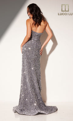A woman poses with her back to the camera in the Lucci Lu 1332 Sequin and Velvet Long Prom Dress. The silver gown features sparkling sequins, a strapless neckline, and a long, dramatic hem against a white backdrop.