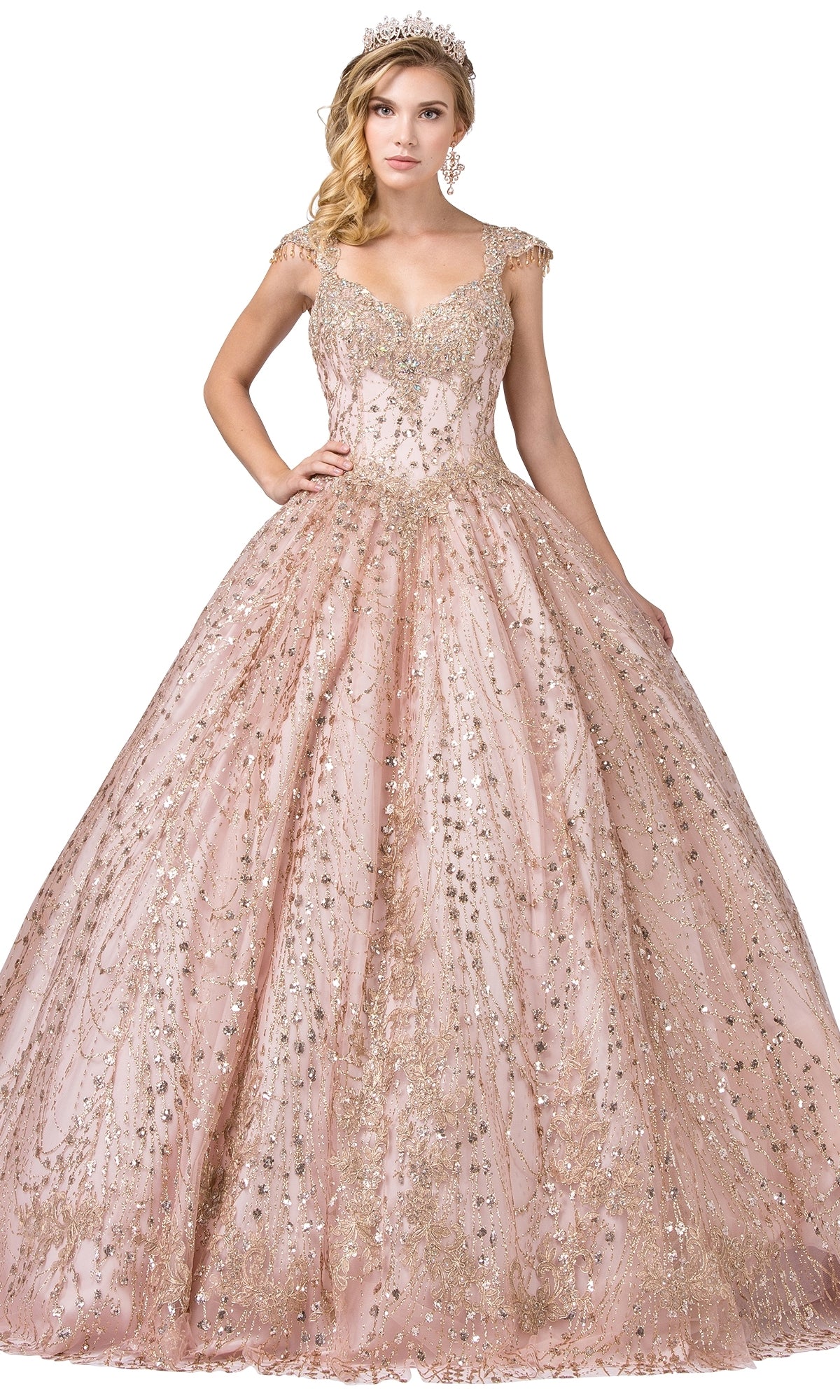 A woman in the Quinceanera Dress 1397 by Dancing Queen—a sparkling, ornate blush pink A-line ball gown with gold embellishments, cap sleeves, and a tiara—stands against a white background.